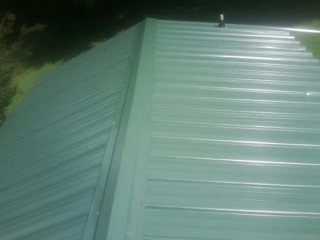 New green metal panels meeting at the ridge of a roof — Flat Roof Repair work by our crew in Ponte Vedra