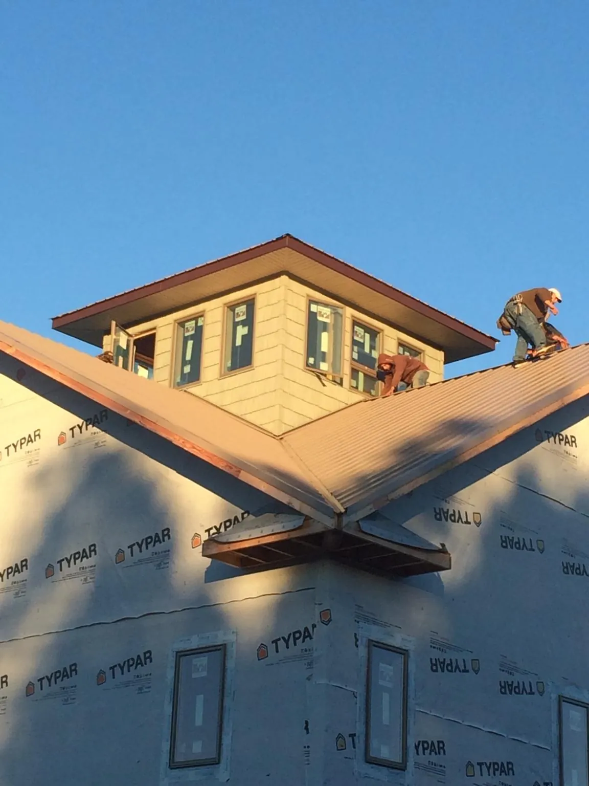 Roofers working around a rooftop cupola on a new metal roof at sunset — Roof Waterproofing in Ponte Vedra by Roofing Brothers